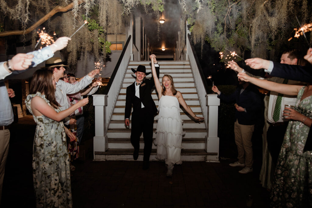 Newlyweds' sparkler exit at Moncks Corner wedding venue - bride and groom walking through tunnel of sparklers held by guests